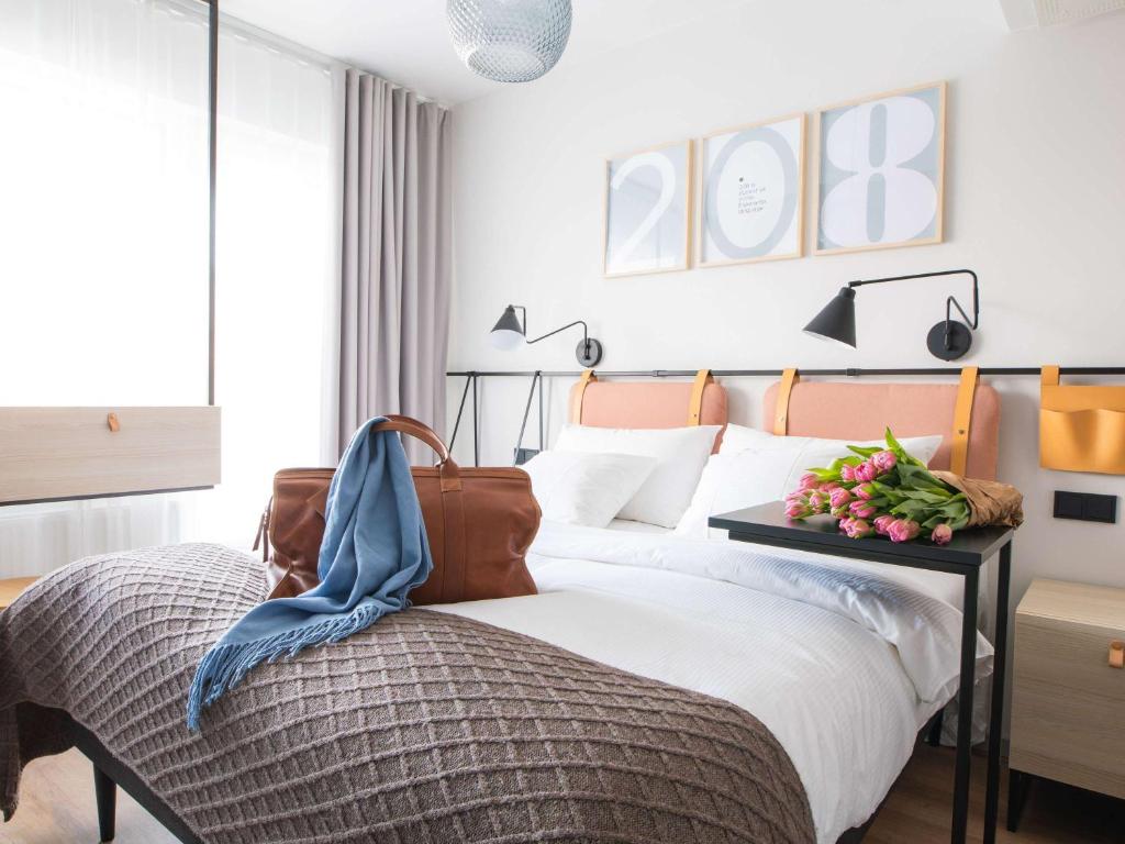 Un dormitorio con una cama y una mesa con flores. en Oru Hub Hotel Tallinn - Handwritten Collection en Tallin