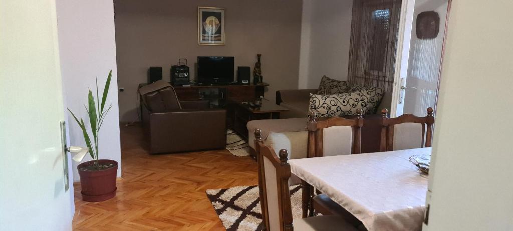 een woonkamer met een tafel, een stoel en een bank bij Apartment TiBi in Kumanovo