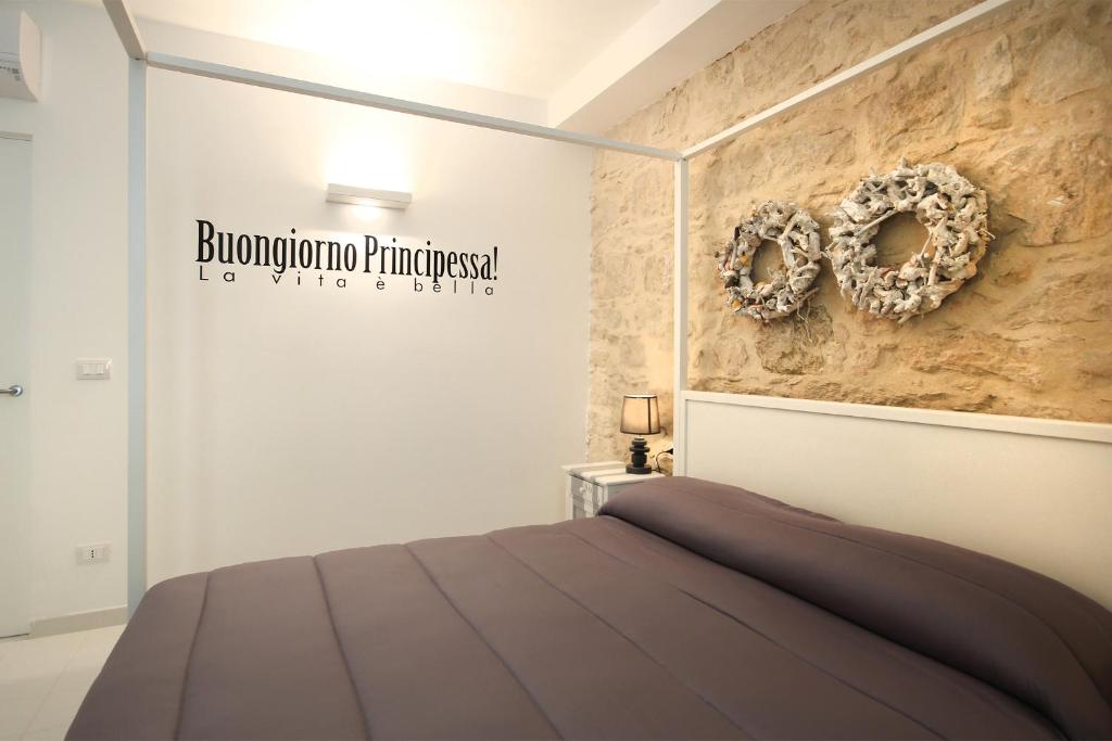 een slaapkamer met een bed en een bord aan de muur bij siciliacasevacanze - Marina Domus in Marina di Ragusa