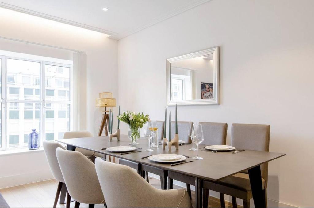 uma sala de jantar com uma mesa com cadeiras e um espelho em Lovely room em Londres