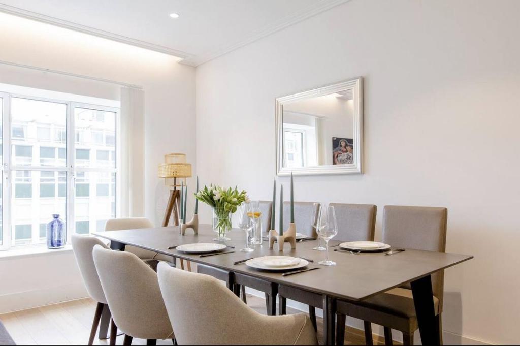 a dining room with a table with chairs and a mirror at Home Stay - Coven Garden in London