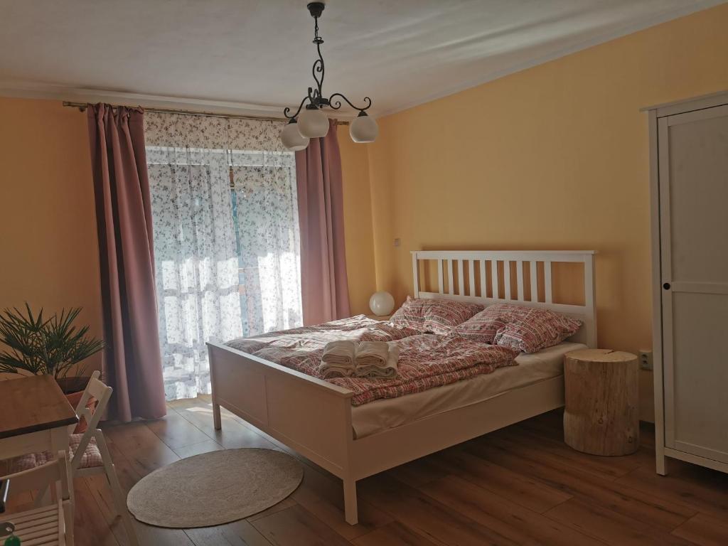 Apartmán PAWLONIA في ترينتشياسكي تيبليسي: غرفة نوم بسرير ونافذة كبيرة