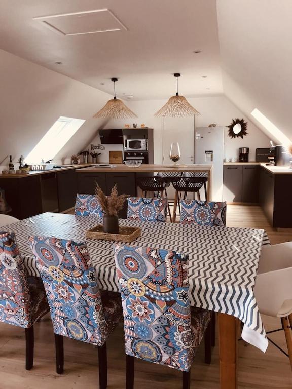 une table de salle à manger avec des chaises et une cuisine dans l'établissement Ker-Lina sea view, calm guaranteed, à Plounévez-Lochrist