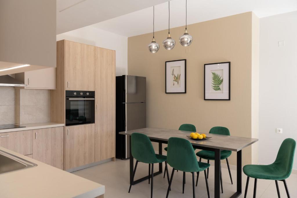 cocina con mesa de comedor y sillas verdes en Mela Luxury Apartments, en Maroulás