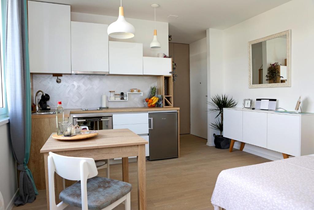 a kitchen with white cabinets and a wooden table and chairs at Studio CAMINO with parking in Zadar