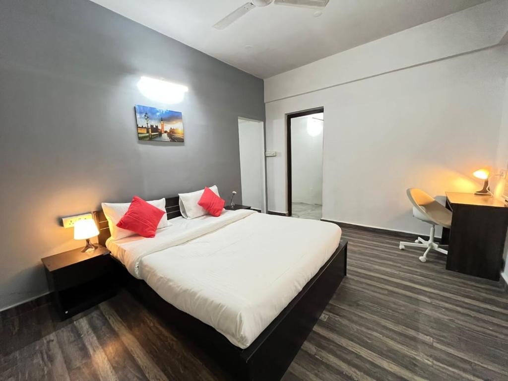 1 dormitorio con cama con almohadas rojas y escritorio en BedChambers Serviced Apartments en Hyderabad