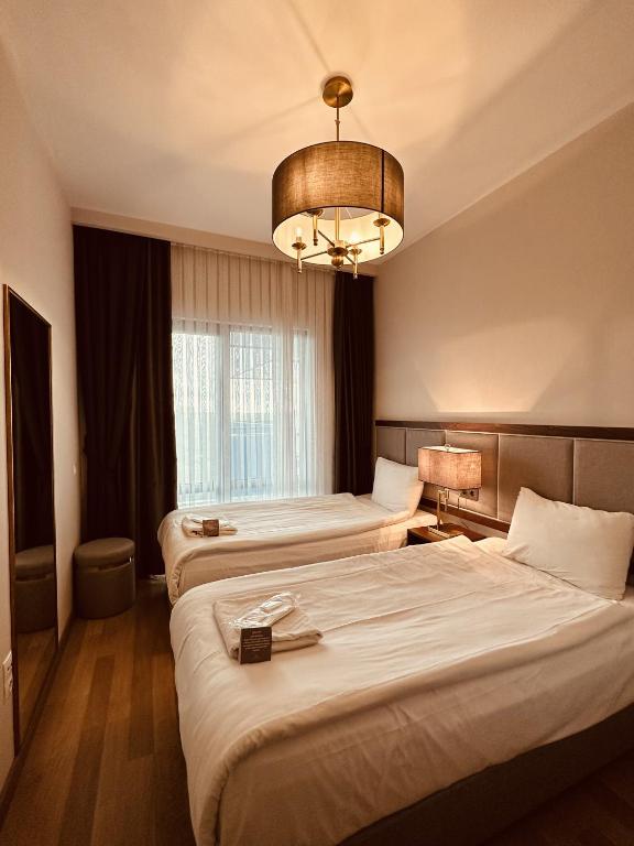 a hotel room with two beds and a chandelier at Maslak Aparts in Istanbul