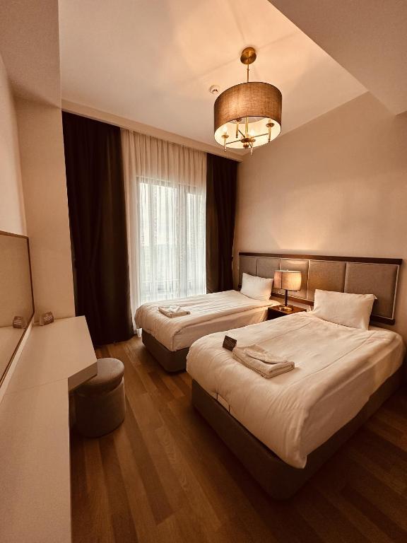 a hotel room with two beds and a chandelier at Maslak Aparts in Istanbul