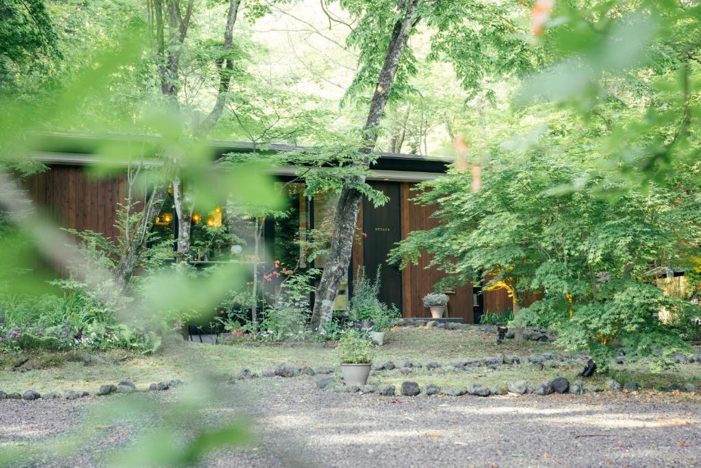 una cabaña en el bosque con árboles y plantas en La Maison Karuizawa, en Karuizawa