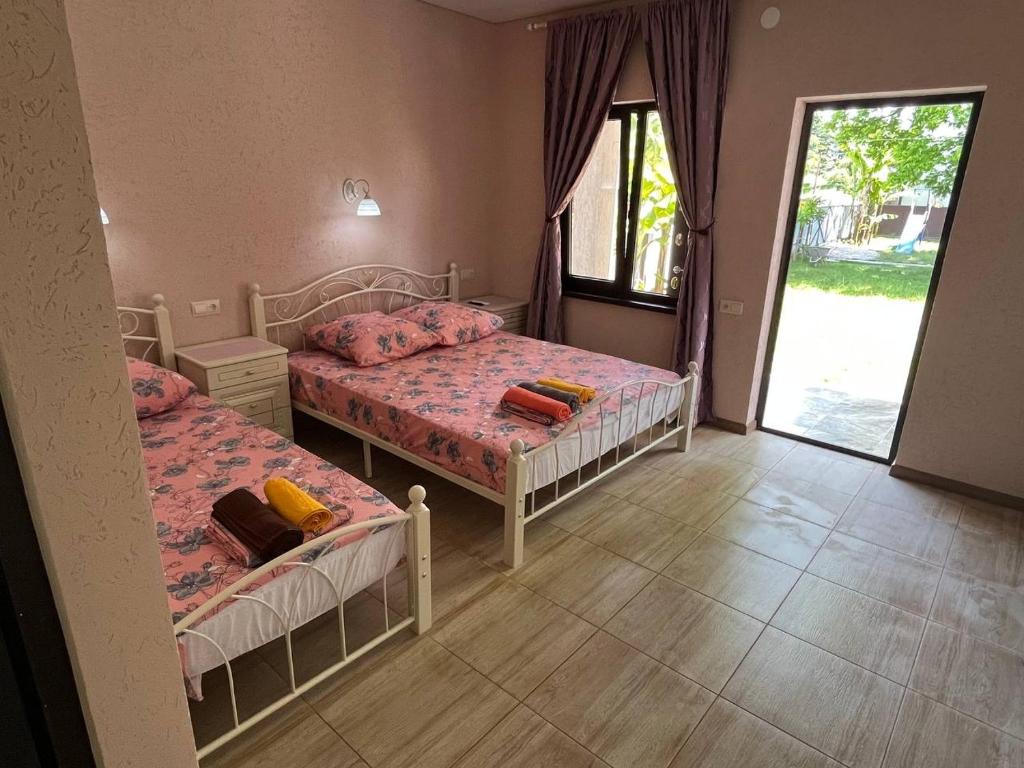 a bedroom with two beds and a large window at Guesthouse Pekan in Pizunda