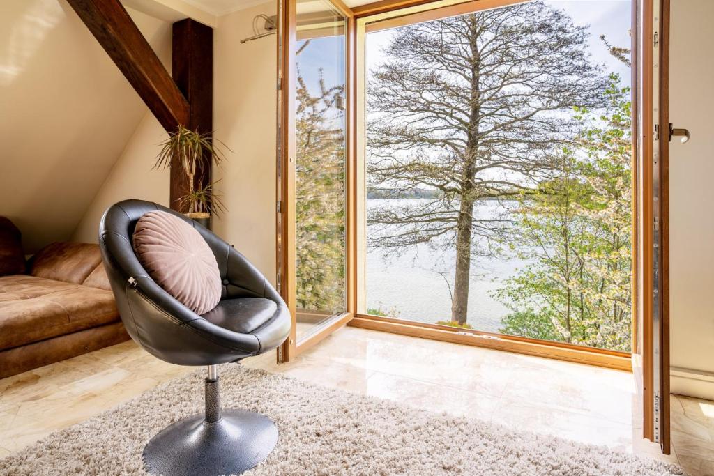a room with a chair and a large window at Apartament Ukiel z widokiem na jezioro in Olsztyn