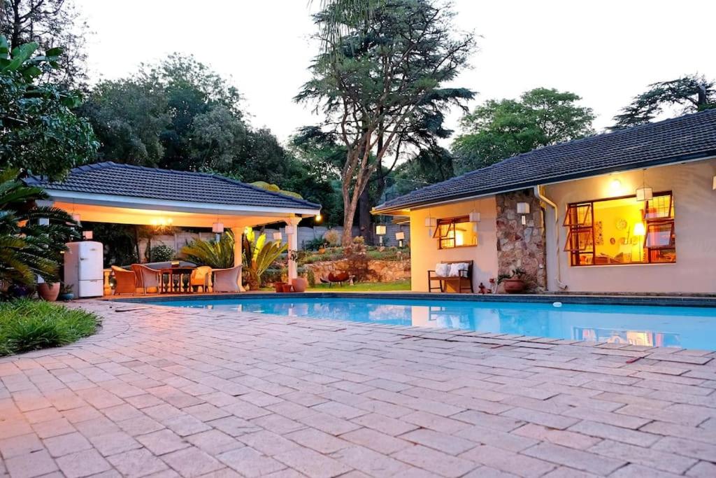 ein Haus mit einem Pool vor einem Haus in der Unterkunft 2 bedroom cottage with Sandton skyline vista in Johannesburg
