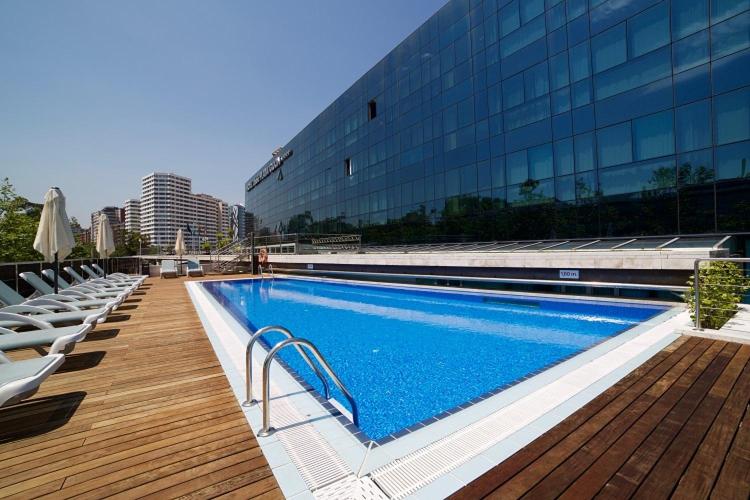 uma piscina com espreguiçadeiras ao lado de um edifício em Abba Playa Gijón em Gijón