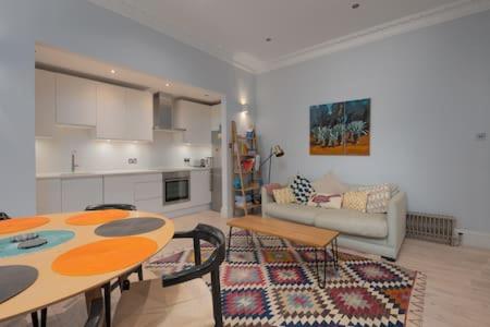 een woonkamer met een tafel en een bank bij Trendy Hampstead Flat RH7 in Londen
