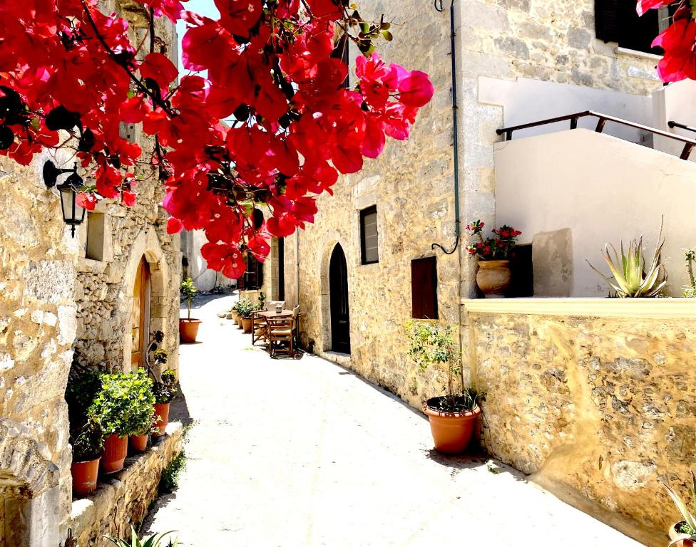 an alley with red flowers hanging from a building at Lithos House and Studios in Kissamos