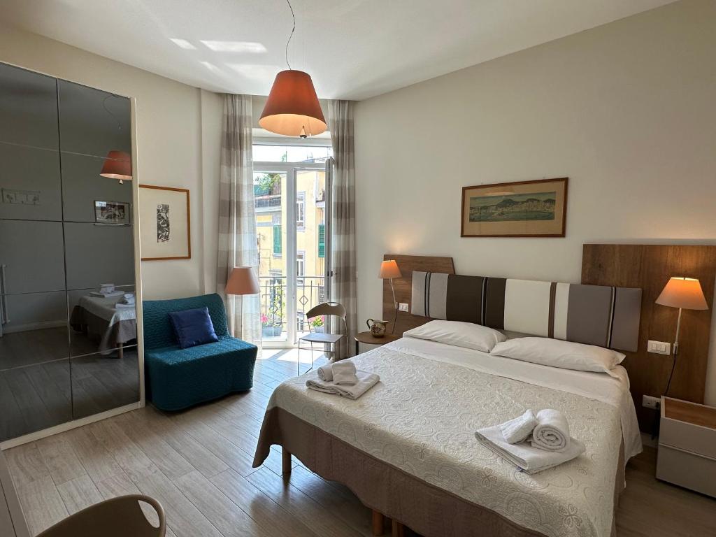 ein Schlafzimmer mit einem großen Bett und einem blauen Stuhl in der Unterkunft Domus Luca - Central Rooms in the Heart of Naples in Neapel