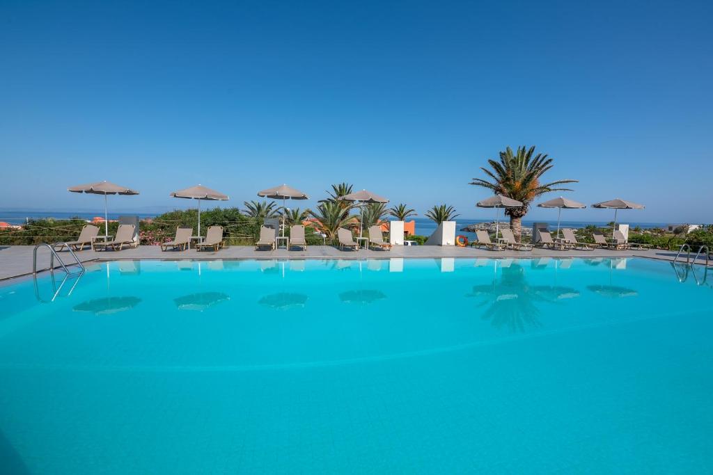 a large blue swimming pool with chairs and umbrellas at Georgia Vicky Studios & Apartments in Stavros