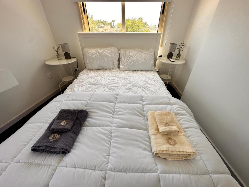 uma grande cama branca com duas toalhas e uma janela em Aphrodites Suite em Pafos