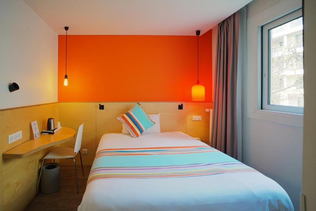 a bed in a room with an orange wall at La Regence in Courbevoie