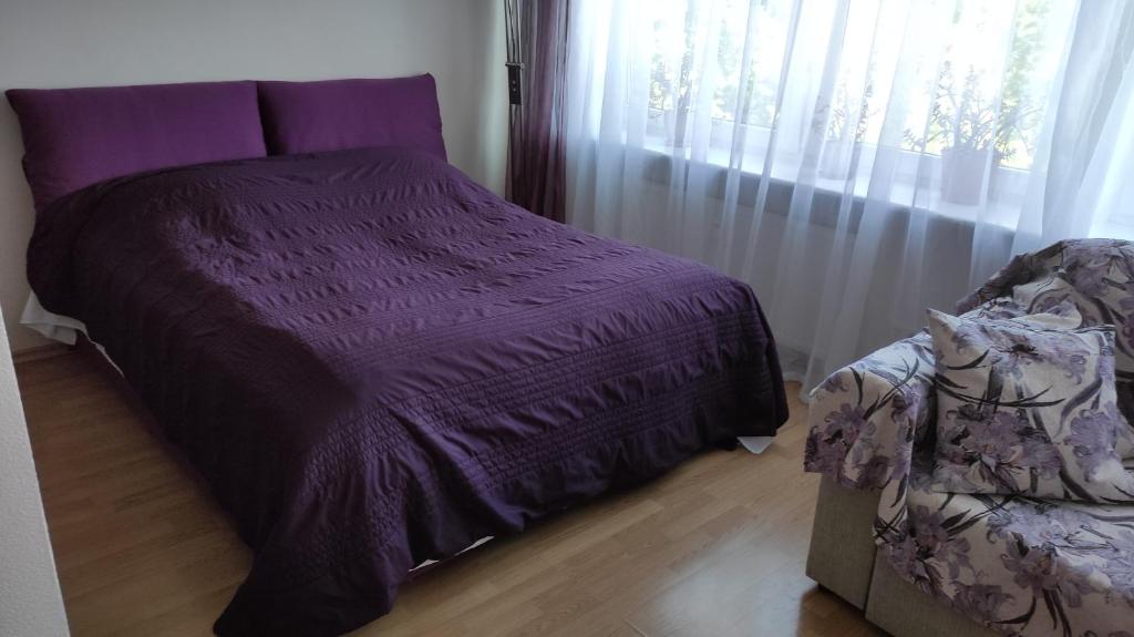 a purple bed in a room with a window at Astra City Centre Apartment in Tallinn