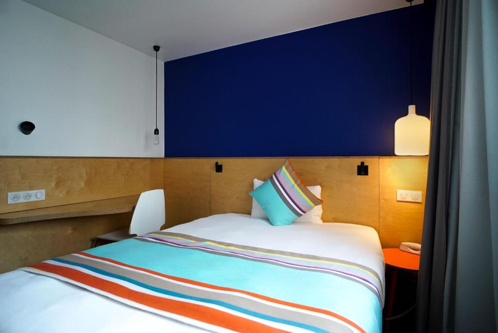 a bedroom with a large bed with a blue wall at La Regence in Courbevoie
