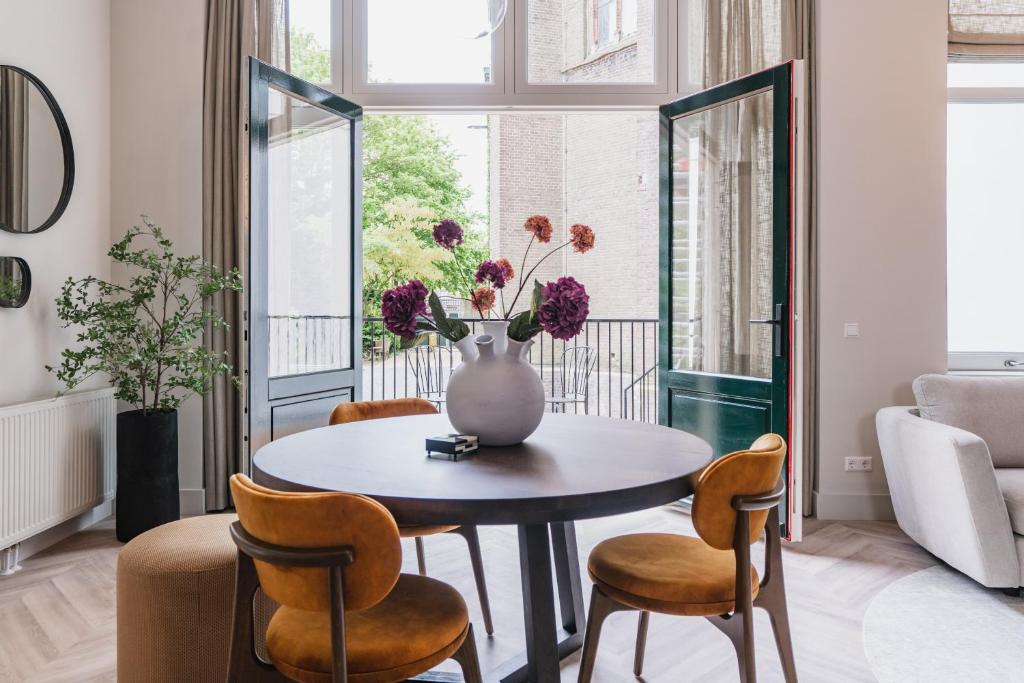 Shortstay - De Pastorie, Gouda في خودا: غرفة طعام مع طاولة وكراسي و مزهرية مع الزهور