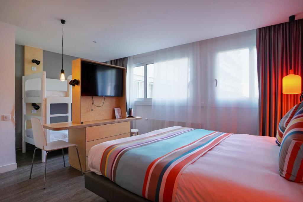 a bedroom with a bed and a desk with a television at La Regence in Courbevoie