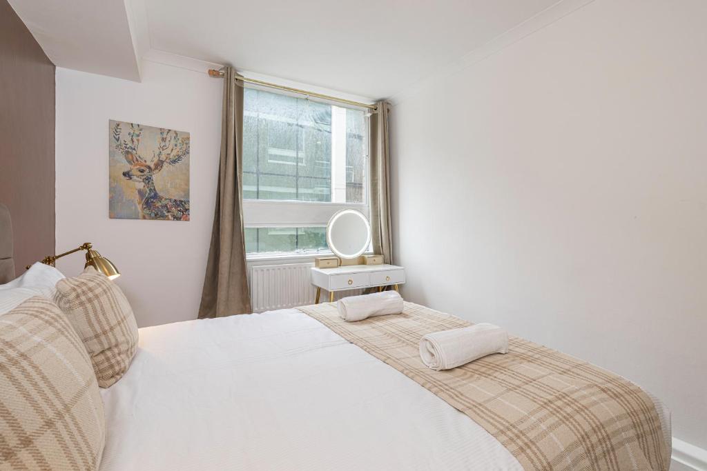 a bedroom with a white bed and a window at Lovely apartment near Hyde Park & Oxford St in London