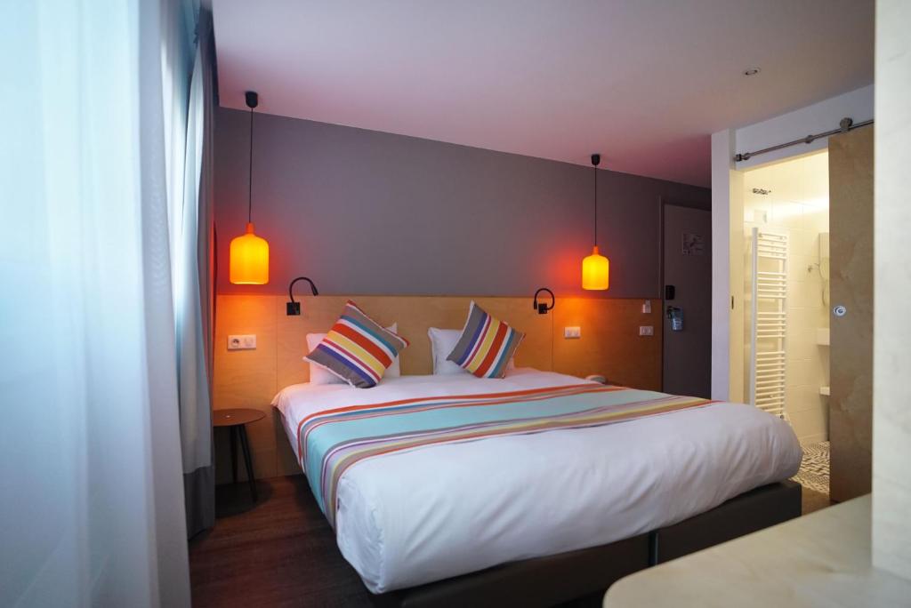 a bedroom with a large bed with two pillows at La Regence in Courbevoie