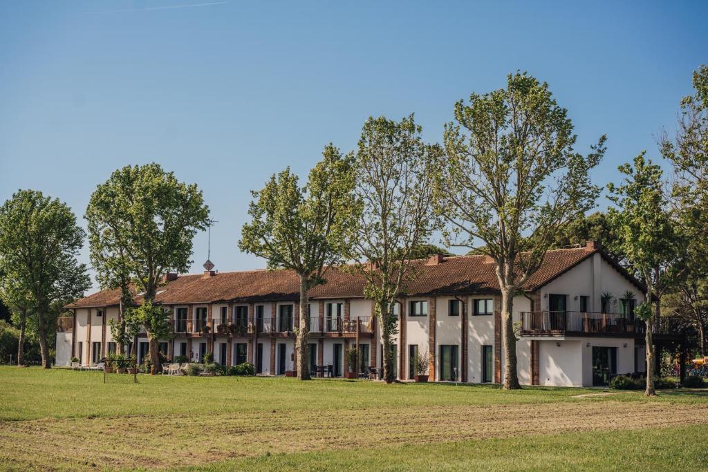 a large building with trees in the foreground at Residenze Di La' Dal Fiume in Caorle