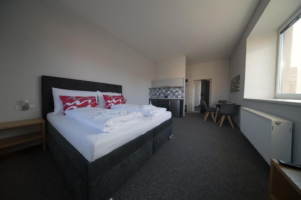 1 dormitorio con 1 cama grande con almohadas rojas y blancas en Replay apartmány, en Frenštát pod Radhoštěm