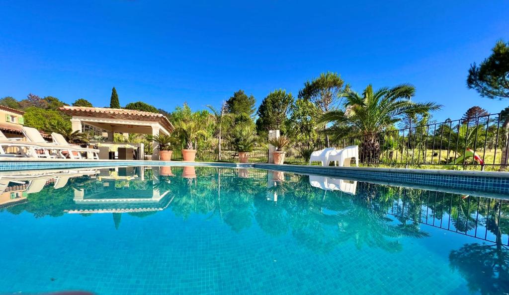 basen z niebieską wodą i palmami w obiekcie Villa La Source 83 - room close to St Tropez w mieście Cogolin