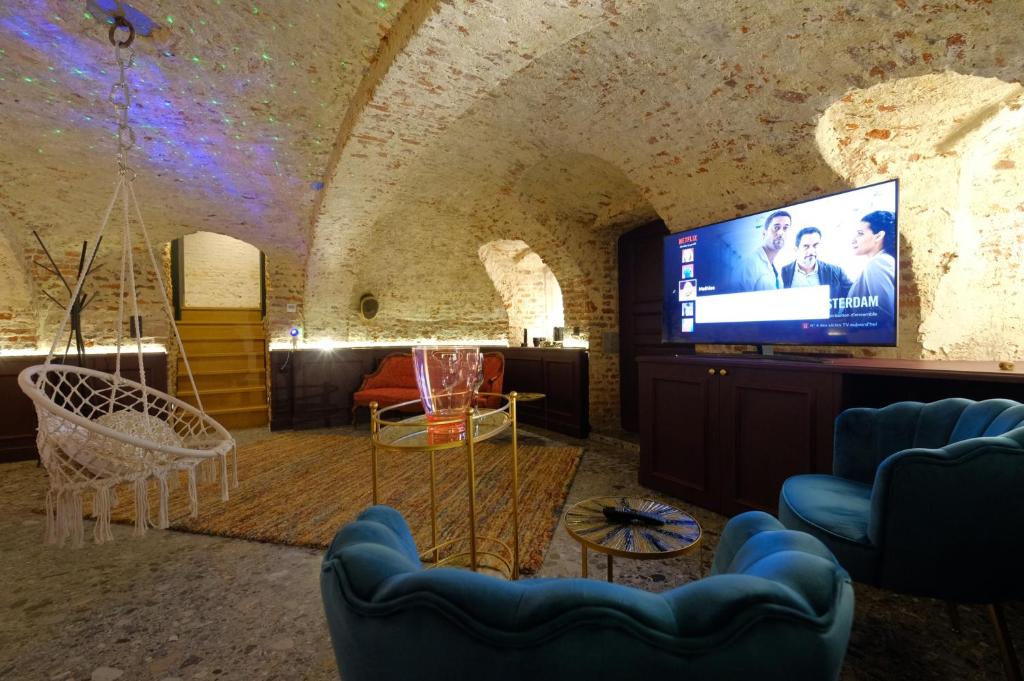 a living room with a tv and a couch at Secret Jacuzzi Mons - Parking privé gratuit in Mons