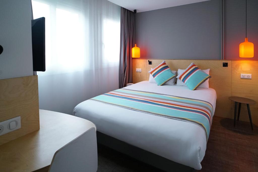 a hotel room with a large bed with colorful pillows at La Regence in Courbevoie