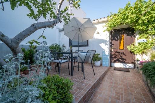 een patio met een tafel en stoelen en een parasol bij Sugar house in Pag