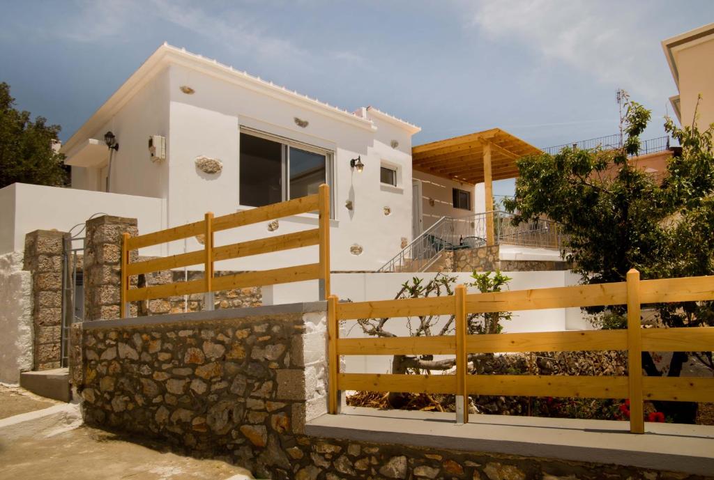 a white house with a wooden fence at Maria's Seaside Home in Kalymnos