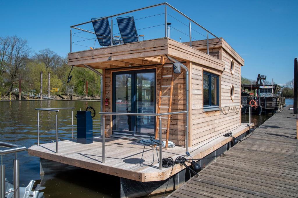 漢堡的住宿－Undine - Wunderschönes Tiny Hausboot，水面上的一个码头上的一个小房子