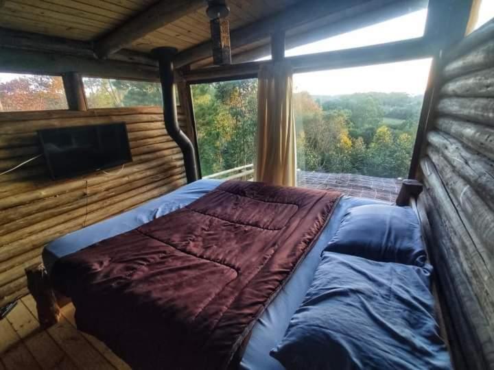 a bed in a room with a large window at Cabana rústica estilo logcabin. in Osório