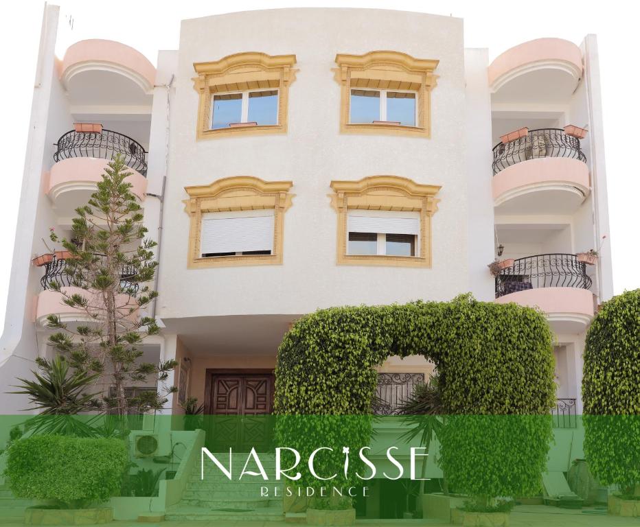 un revestimiento de un edificio blanco con un seto verde en NARCISSE RESIDENCE, en Hammam Sousse