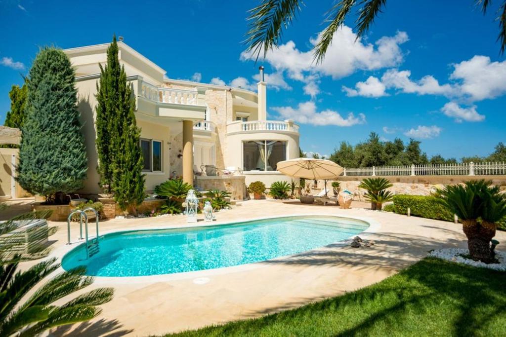 a villa with a swimming pool in front of a house at Villa Kokalis Resort in Gouves