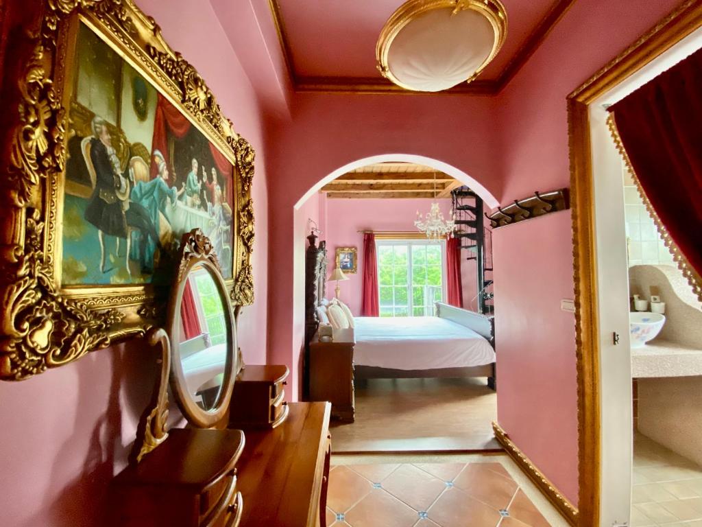 a pink bedroom with a bed and a mirror at England Castle B&amp;B in Wujie