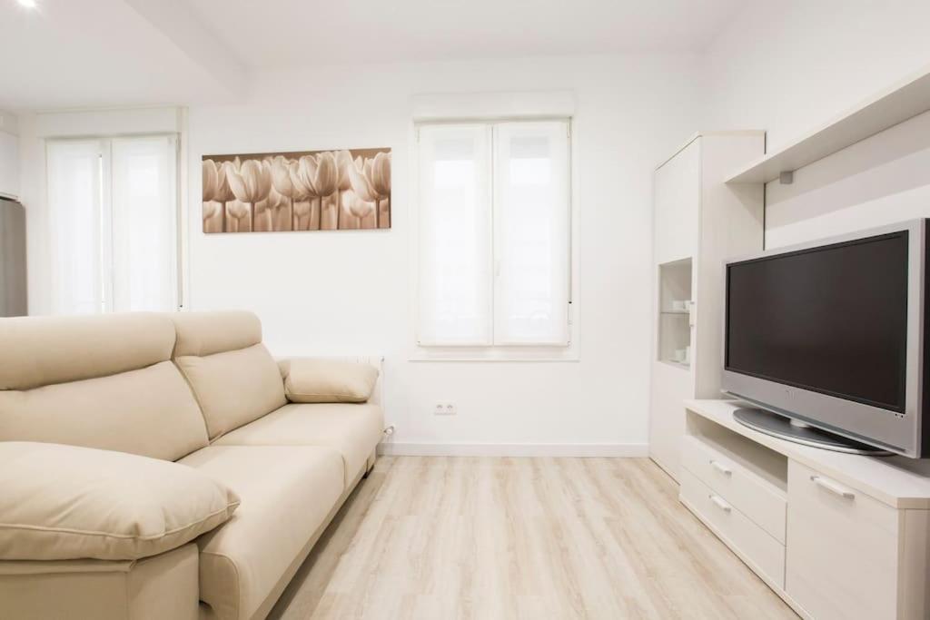 Biały salon z kanapą i telewizorem z płaskim ekranem w obiekcie Piso en el centro de Bilbao, frente a la Alhóndiga w mieście Bilbao