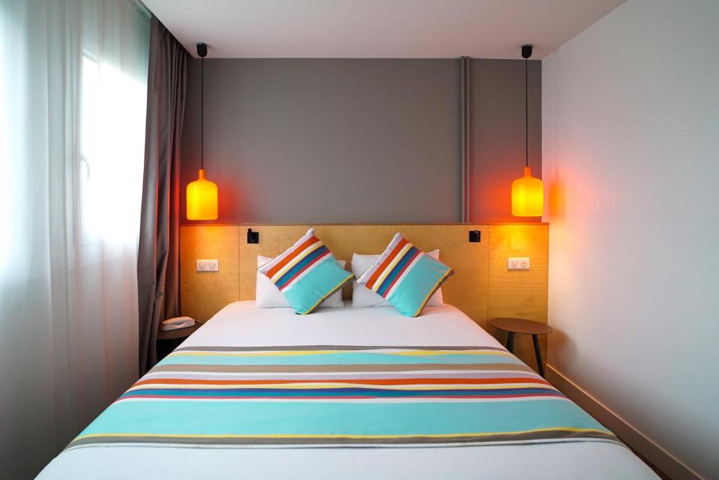 a bedroom with a large bed with colorful pillows at La Regence in Courbevoie