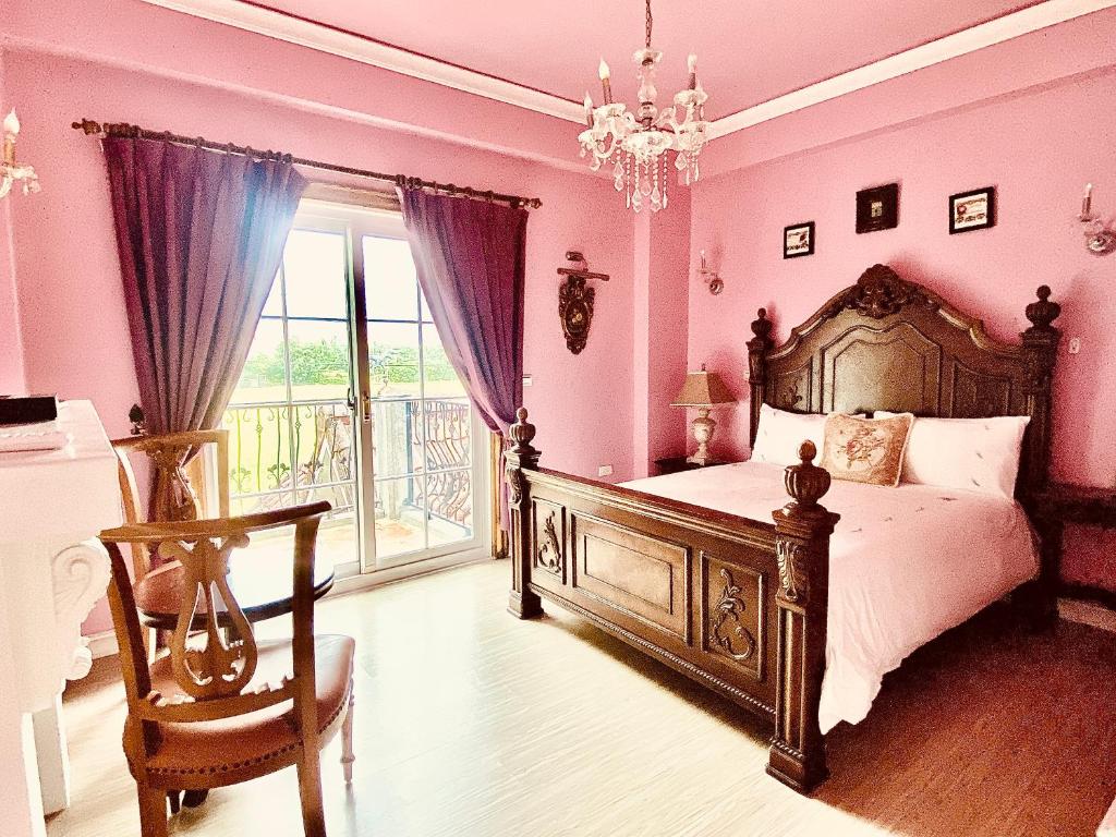 a bedroom with a bed with pink walls and a chandelier at England Castle B&amp;B in Wujie