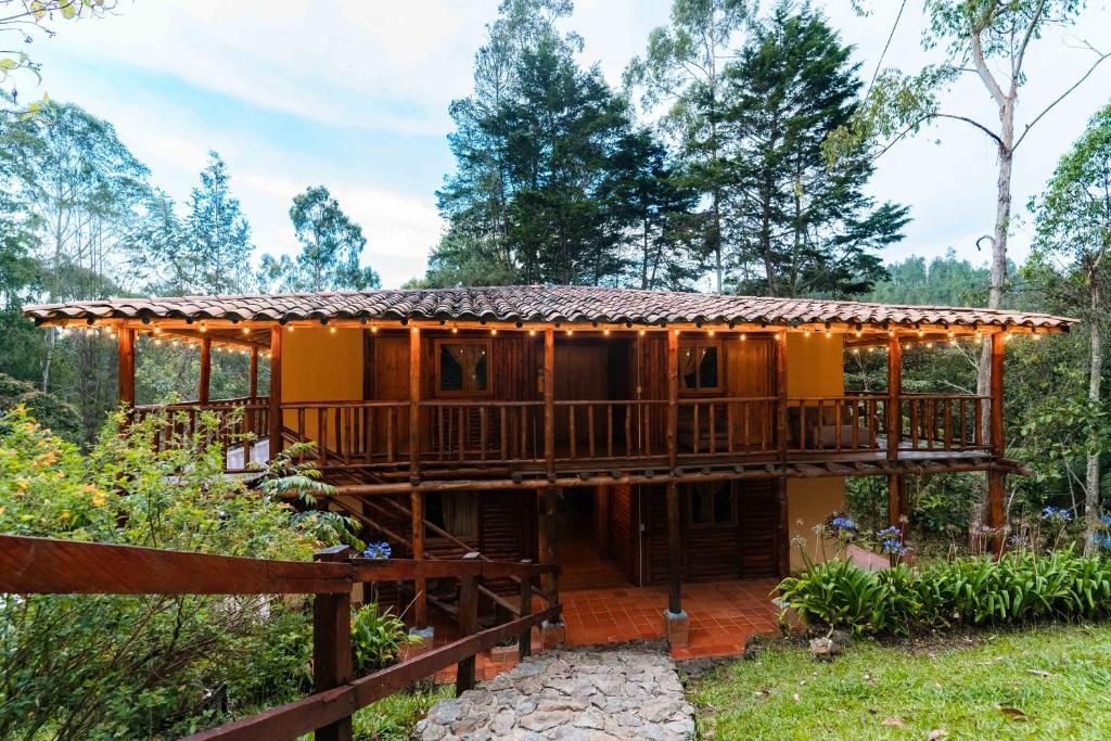ein Haus mit einer Terrasse in der Mitte eines Gartens in der Unterkunft Alma Hotel Campestre in Santa Elena
