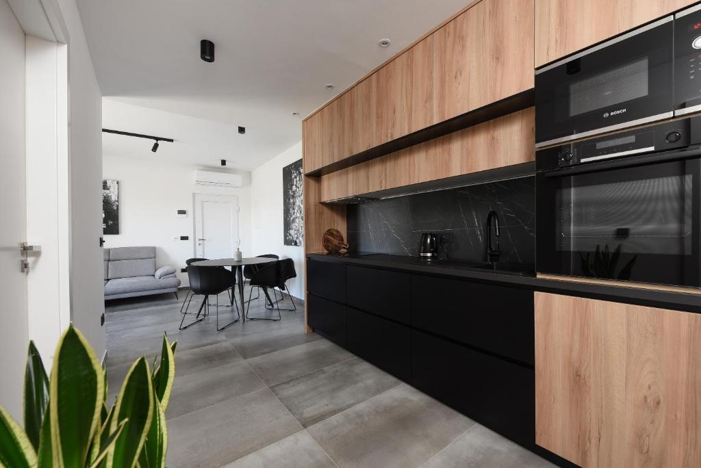 a kitchen with black cabinets and a living room at Luxury apartment N in Zadar