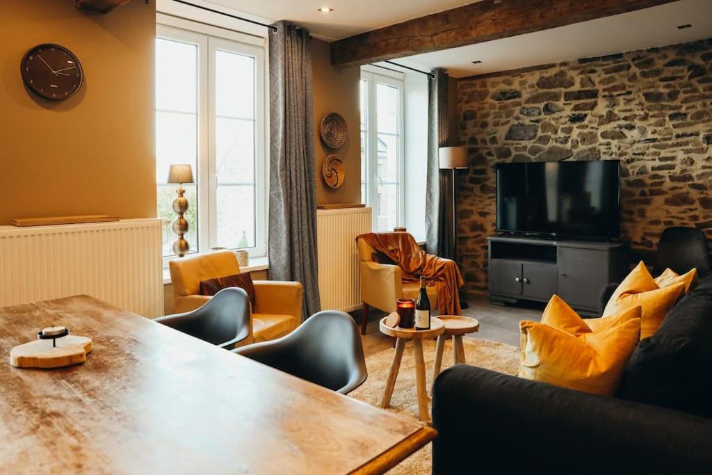 ein Wohnzimmer mit einem Tisch und einem TV in der Unterkunft Le Theutois Appartement 6p - Theux - 1er étage in Theux