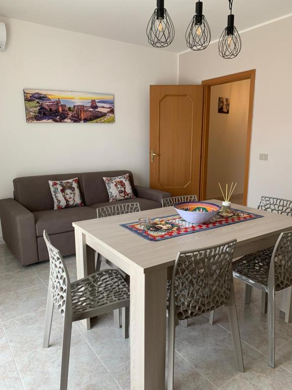 uma mesa e cadeiras numa sala de estar com um sofá em Casa Vacanza Sicily House em Gaggi