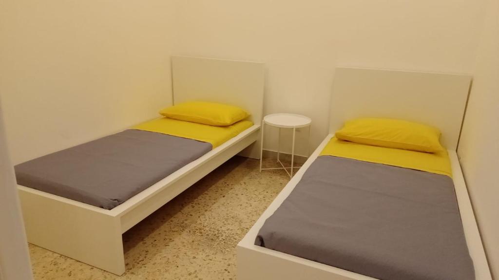 Duas camas num pequeno quarto com almofadas amarelas em East Holiday Apartment 1 & 2 em Nápoles