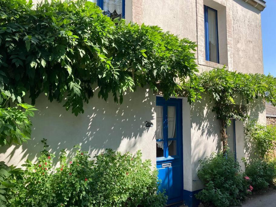dom z niebieskimi drzwiami i krzakami w obiekcie Petite maison de pêcheur w mieście Île-aux-Moines